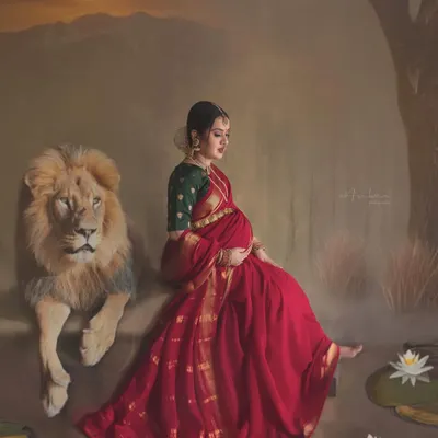 Inspired by the goddesses of Indian folklore, this conceptual maternity portrait captures the quiet strength and fierce love of a mother. The composition, with the mother in a traditional red saree seated beside a lion, creates a powerful, painterly image of feminine power.