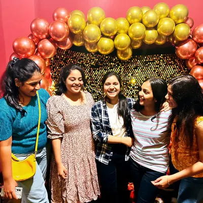 A candid moment of laughter between friends during a celebration at my private theatre. The gold and red balloon arch with a sequin wall makes for a glamorous photo background.