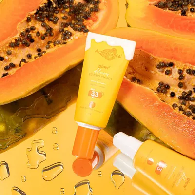 A vibrant shot for Aqualogica, using fresh papaya and a reflective surface to emphasize the product's natural ingredients and glowing effect.