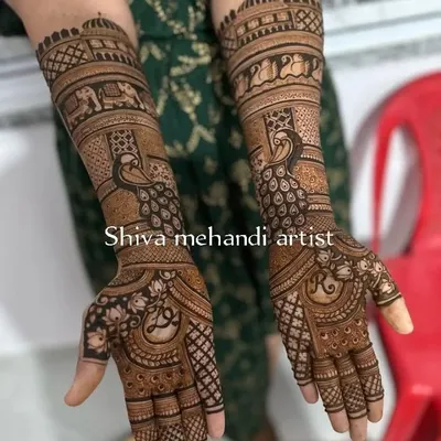 A beautiful example of traditional mehendi featuring majestic peacocks on the forearms. The palms have a delicate floral pattern with the bride's initial.