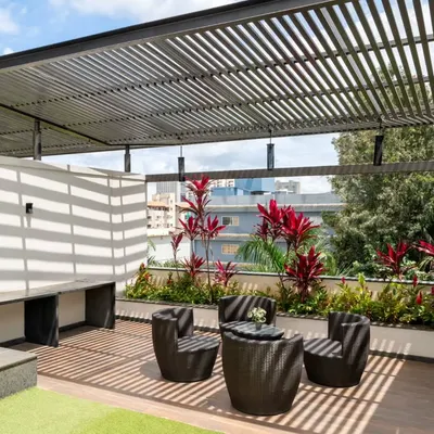 A wider view of the terrace, showing how the different elements work together. The design includes a mix of hardscape, soft artificial grass, and a planter bed, creating distinct zones for seating and circulation while maintaining a cohesive, modern aesthetic.