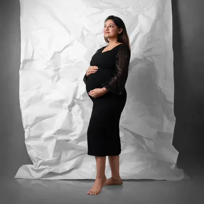 A timeless maternity portrait that will never go out of style. The combination of a simple black dress and a clean, textured backdrop creates a sophisticated and elegant look.