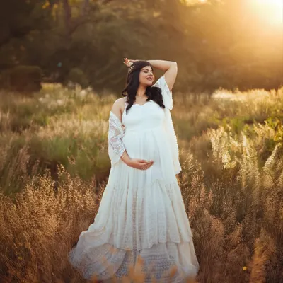 A solo portrait of the mom to be, basking in the warm glow of the setting sun. The flowing white gown and the natural field create a truly ethereal pregnancy photograph.