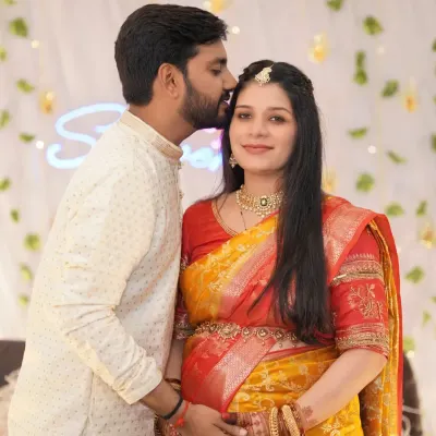 A tender moment from a baby shower celebration. The father-to-be kisses his wife's forehead as she smiles, capturing the love and excitement of the day.