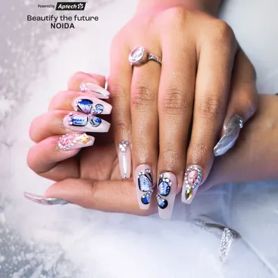 A close-up of long, coffin-shaped acrylic extensions featuring detailed butterfly wing art. Our students learn to build strong, elegant extensions and embellish them with multi-dimensional designs and rhinestones.