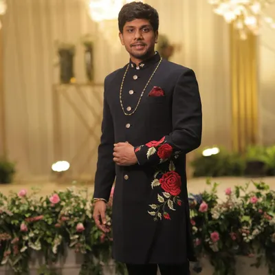 A masterpiece of traditional tailoring. This client is wearing a custom navy blue sherwani featuring stunning red rose embroidery, a design we created to symbolize a sibling bond for a wedding.