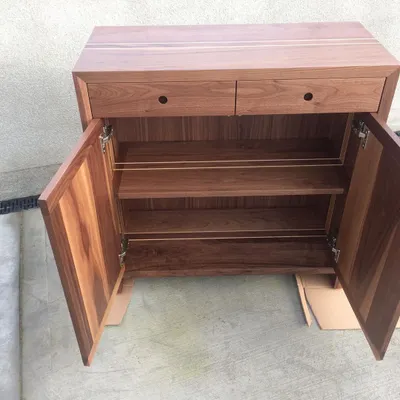 A solid walnut sideboard featuring a fine ash inlay, custom-turned drawer pulls, and internal shelving. This piece was part of a large, prestigious project that also included tables, lamps, and mirrors.