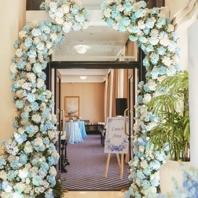 A breathtaking floral arch in shades of blue and white creates a grand yet welcoming entrance. The dense hydrangeas and roses set a luxurious and romantic tone from the moment guests arrive.