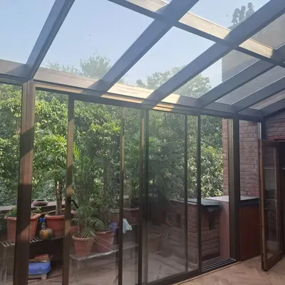 A completed glass sunroom that connects the main house to a terrace filled with plants. The sliding glass doors allow the space to be opened up completely, creating a true indoor-outdoor experience.