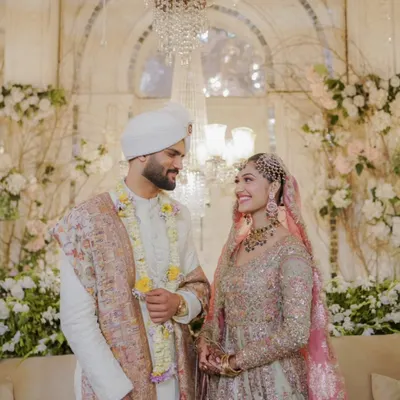 A beautiful moment captured in a stunningly decorated venue. The elegant white and floral backdrop, combined with a grand crystal chandelier, created a regal and romantic setting for this couple.