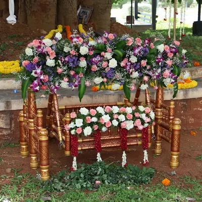 This ornate wooden thottilu (cradle) is decorated with an abundance of fresh flowers for an outdoor naming ceremony. The rental includes the cradle and the complete floral arrangement.