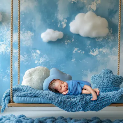A newborn rests peacefully on a dreamy swing set against a sky-blue backdrop, showcasing our creative and artistic approach to newborn photography. We design unique, safe, and beautiful sets like this in our Bangalore studio.