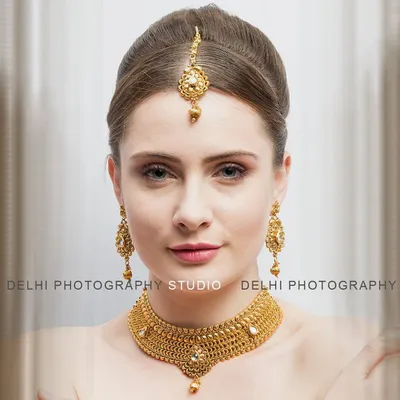 A perfect example of a beauty and jewelry headshot. The lighting is focused to highlight the model's features and the intricate details of the traditional gold jewelry set.