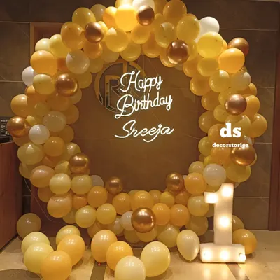 A gorgeous first birthday balloon ring in shades of yellow, white, and gold. This elegant backdrop is personalized with a neon sign and a light-up marquee number '1'.
