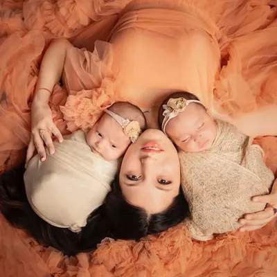 A mother's embrace with her two precious newborn twins. This artistic top-down shot, with the babies nestled in her beautiful gown, is a breathtaking portrait of motherhood.