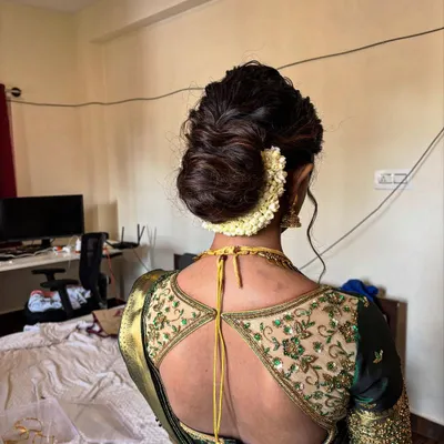 A classic textured low bun, elegantly wrapped with a string of fresh jasmine flowers ('Gajra'). This is a timeless choice for a saree look.