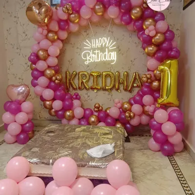 An elegant balloon ring decoration for a first birthday at home. We used shades of pink and gold to create this beautiful photo backdrop behind the cake-cutting area.