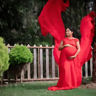 The 'flying fabric' effect is a dramatic and beautiful way to highlight your baby bump. We use long, flowing gowns like this red one to create breathtaking pregnancy portraits in natural settings.