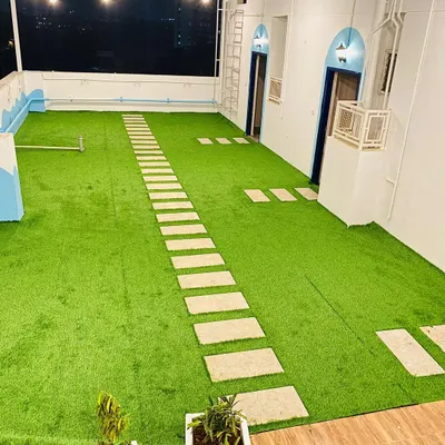A wide view of the rooftop cafe project, showing the expansive area covered with our artificial turf. We integrated a long stone pathway for foot traffic, ensuring durability and design cohesion.
