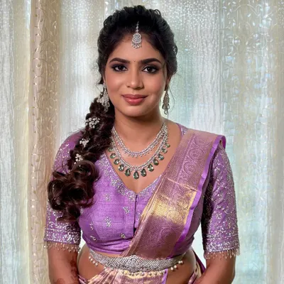 A beautiful engagement look for Charu. The makeup features a soft smokey eye and a neutral lip, paired with a modern braided hairstyle and a lovely lavender saree.