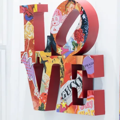 'Love Unleashed' by Khushi Gursale & Sarvesh Chavan. This metal artwork reinterprets Robert Indiana’s iconic LOVE sculpture as a cut-out layered with a vibrant pop art collage of brands like Gucci and Prada.