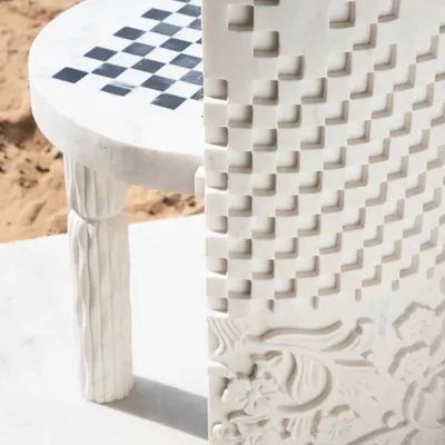 A detailed look at the Dori Patti chair, highlighting the contrast between the smooth, checkered seat and the intricately carved back panel. Each detail is a nod to traditional Indian craft, restored for the modern home.