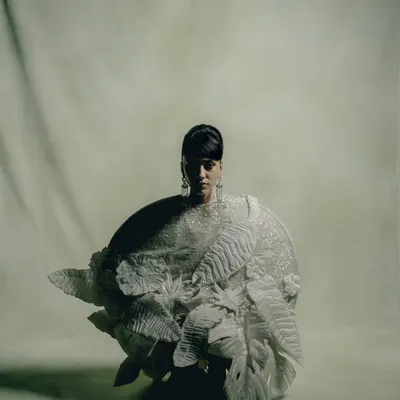 A crouching pose in a Rahul Mishra couture piece. The lighting carves out the intricate, three-dimensional details of the garment, creating a sense of texture and depth.