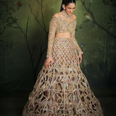 This is what I call a showstopper moment. For this 'Mela Rouge' themed event, we went for a jaw-dropping gold Manish Malhotra lehenga with a unique cut-out overskirt and an off-shoulder blouse. The result was pure fire, a look that's all about high-impact glamour.
