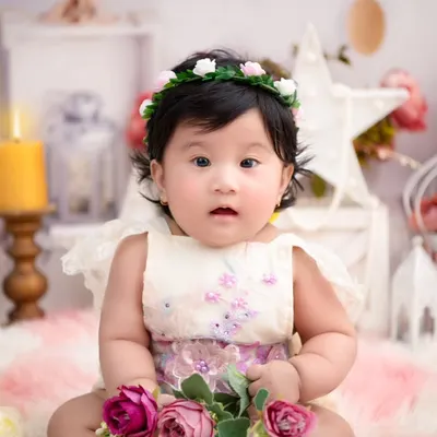 A sweet six-month sitter session. The simple, elegant background with soft floral accents keeps the focus on her adorable expression and new milestone.