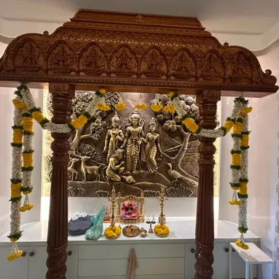 A full view of the decorated pooja mandap for the Khandelwal's Gruhapravesam. The traditional yellow and white flower garlands hang beautifully against the intricately carved wood.