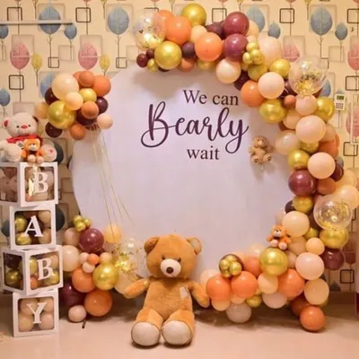 A 'We Can Bearly Wait' teddy bear theme for a baby shower. This setup includes a circular backdrop, a beautiful balloon arch in neutral colors, and cute teddy bear props.