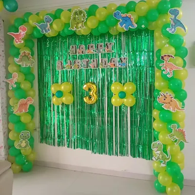 A dinosaur-themed third birthday party. I created a full balloon arch in two shades of green, decorated with various dinosaur cutouts. A matching green shimmer backdrop completes this simple yet effective prehistoric setup.