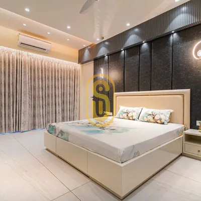 A bright and airy bedroom featuring a dark grey upholstered accent wall with integrated lighting. The custom bed includes built-in storage drawers, demonstrating our focus on functional design.