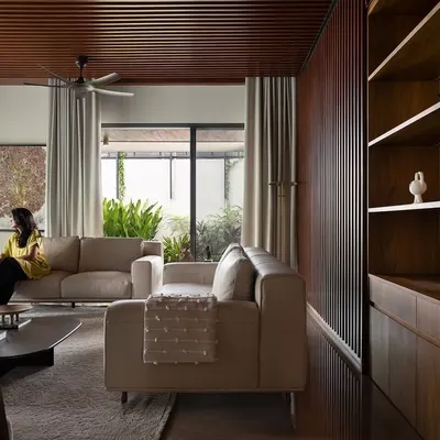 The formal living area in Villa Shakthi combines a warm wood-panelled ceiling with expansive windows, connecting the space to the lush landscape outside. We designed this room to feel both spacious and intimate, perfect for family gatherings or quiet reflection.