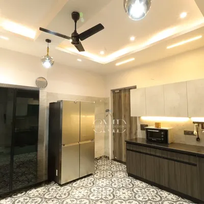 This monochrome-themed kitchen in Noida is a seamless blend of style and practicality, featuring patterned floor tiles and ample storage.