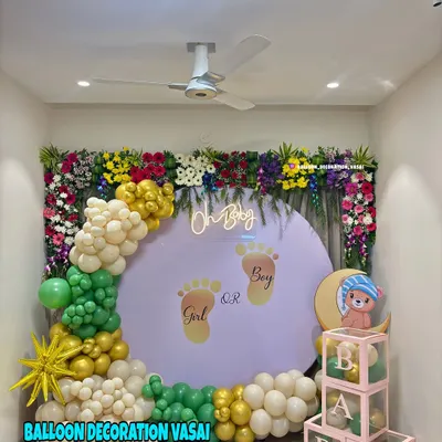 This "Oh Baby" gender reveal backdrop combines a lush floral border with a playful balloon arch in green, gold, and white. The custom backdrop with tiny footprints adds a personal and exciting touch to the celebration.