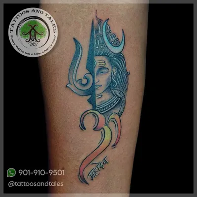A custom design combining Lord Shiva's face with his Trishul and the Om symbol. We used a mix of blue tones and a gradient of color in the script to give this Mahadev tattoo a unique look.