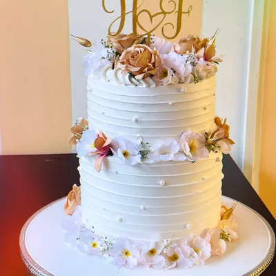 The epitome of wedding elegance. This two-tier premium cake features delicate line work, a custom initial topper, and is adorned with beautiful blush and white florals.