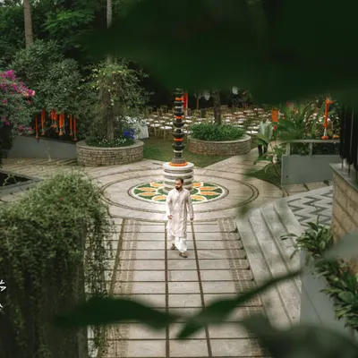 A wide shot capturing the beautiful wedding venue and the groom walking in, setting the scene for the celebration.