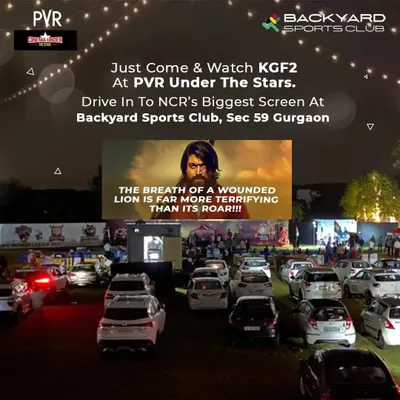 A perfect view of our PVR drive-in cinema setup during a screening of KGF 2. This image shows the large screen and the organized parking for cars, highlighting the unique and comfortable viewing experience we provide.
