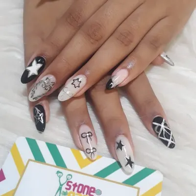 For those who love a bold look. This set features a mix of black and white gel polish with hand-painted stars, bows, and geometric patterns on long almond-shaped extensions.