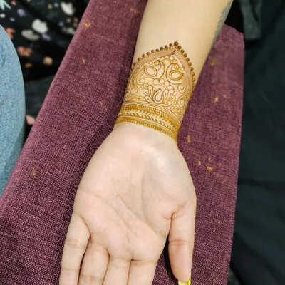 A clear view of the popular wrist cuff or bracelet style mehndi. This design features traditional peacock and lotus motifs in a neat, modern band.