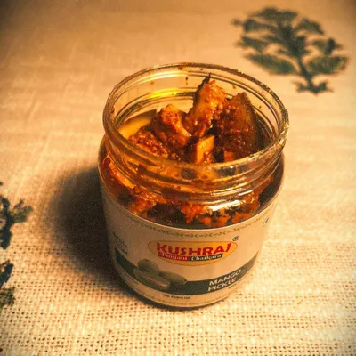 A jar of my classic Mango Pickle, filled with chunky pieces of raw mango and aromatic spices. It's the taste of home in every bite.