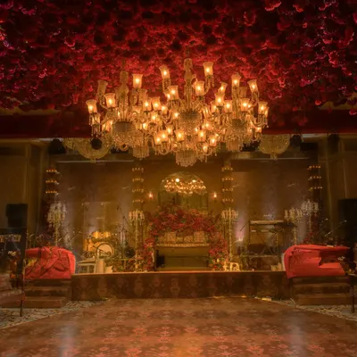A breathtaking view of a reception hall I designed. The ceiling is completely covered in red flowers, with a magnificent crystal chandelier as the centerpiece, creating an atmosphere of pure opulence and romance.