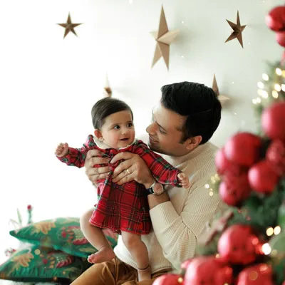 Capturing the lingering joy of the holiday season. This sweet moment between a father and his baby by the Christmas tree shows that the magic lasts long after December 25th.