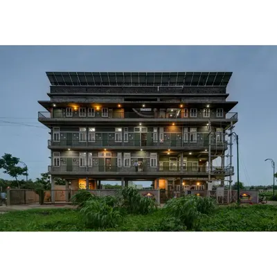 The Action for Social Advancement (ASA) office in Bhopal, illuminated at night. The building is elevated on stilts to handle a water-logged site, and the rooftop is covered with a 20kVA solar PV system, making it energy self-sufficient.