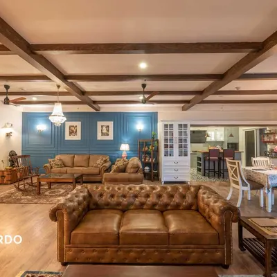 An expansive view of a home where industrial and Victorian styles merge. The open layout connects two distinct seating areas and a dining space, unified by wooden ceiling beams and a consistent color palette, making it ideal for large gatherings.