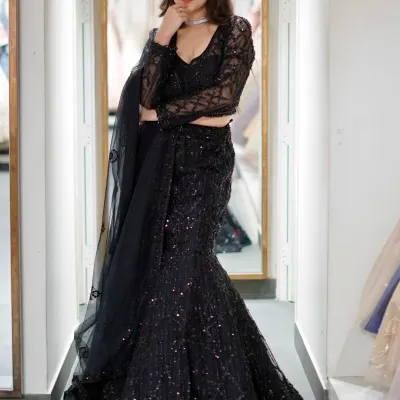 This black fish-cut lehenga is stitched with sass and main character energy. The all-over sequin work and sheer sleeves make it a glamorous choice for a cocktail night or reception.