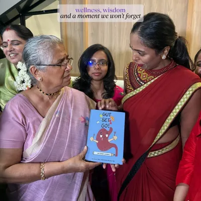 A heartwarming moment of me gifting my book, "Gut, Set, Go!", to an elder, showing the intergenerational appeal of wellness.