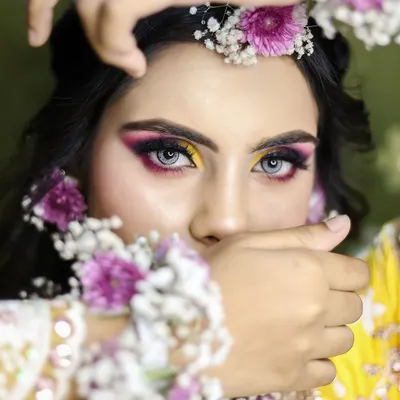 A striking close-up of a Haldi look, featuring vibrant yellow and purple eyeshadow. The floral jewelry is a key element, and I teach you how to incorporate it beautifully into the hair and overall style.